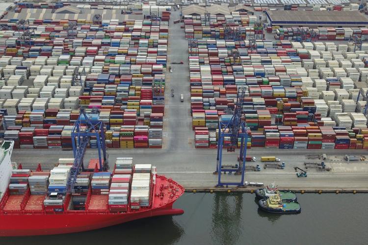 Porto com navio de carga atracado e o pátio lotado de containers