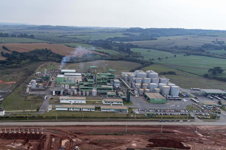 Fábrica em plena atividade numa extensa planície verde, em Lapa, Paraná